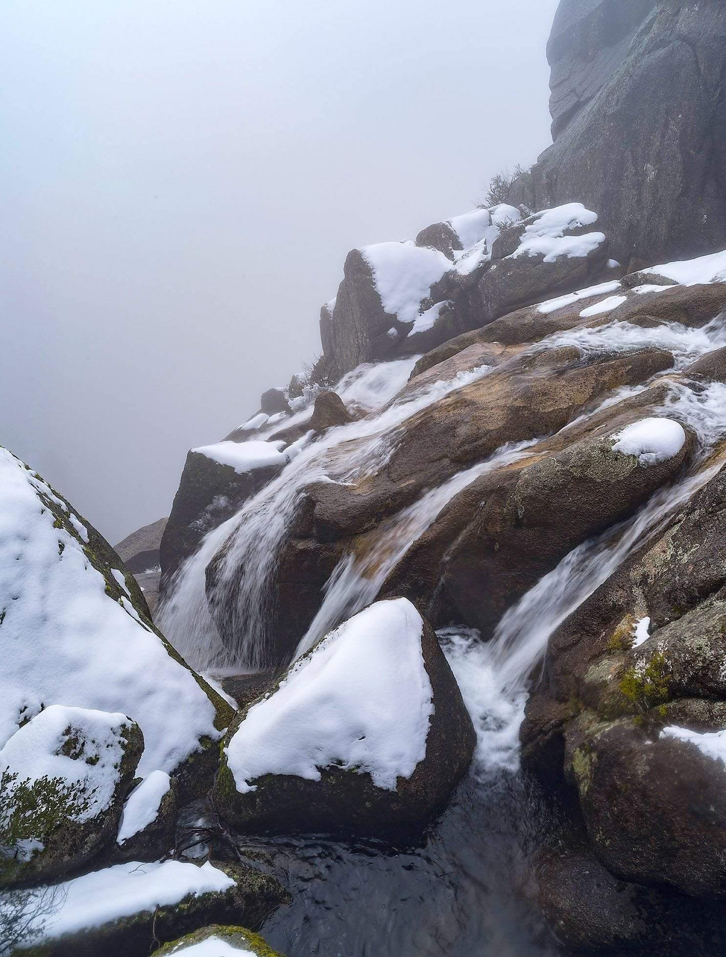 Heavy mountain stones connected together and covered with the fresh wet snow with a flow of small watercourse, Crystal Brook Falls - Mt Buffalo VIC