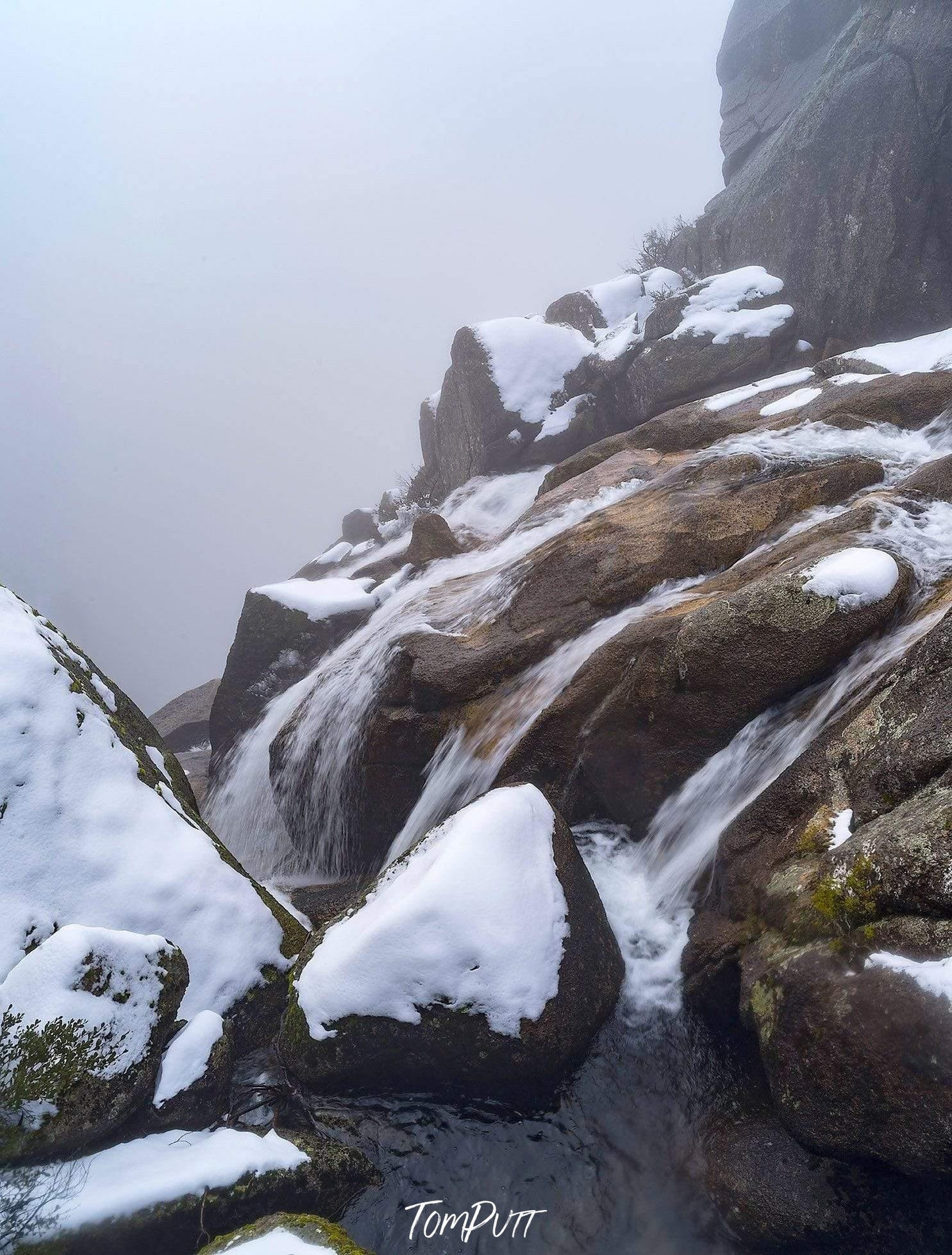 Heavy mountain stones connected together and covered with the fresh wet snow with a flow of small watercourse, Crystal Brook Falls - Mt Buffalo VIC