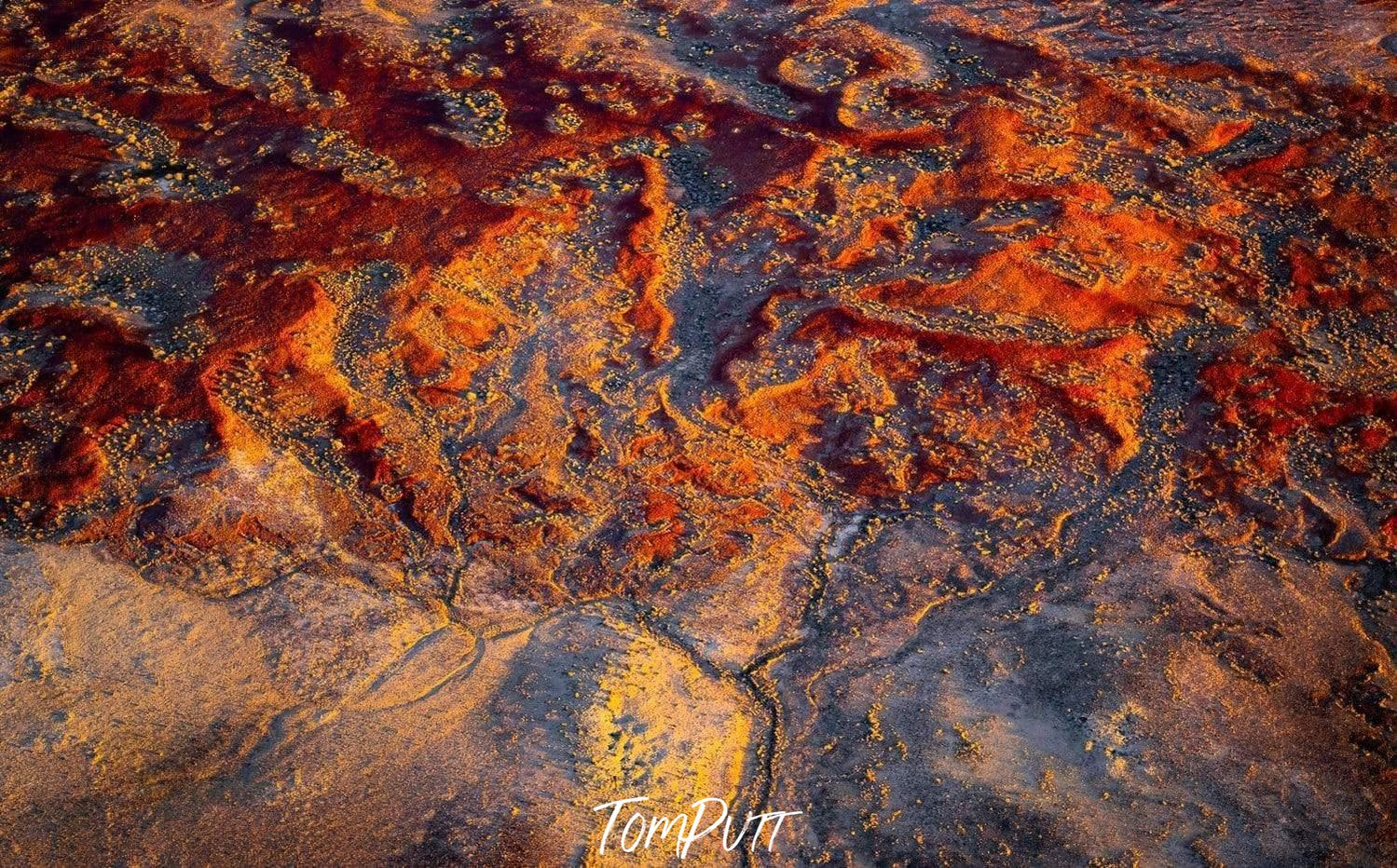 an aerial view of a dark orangish colored desert with different cracks and ups downs of sands, Desert Waves