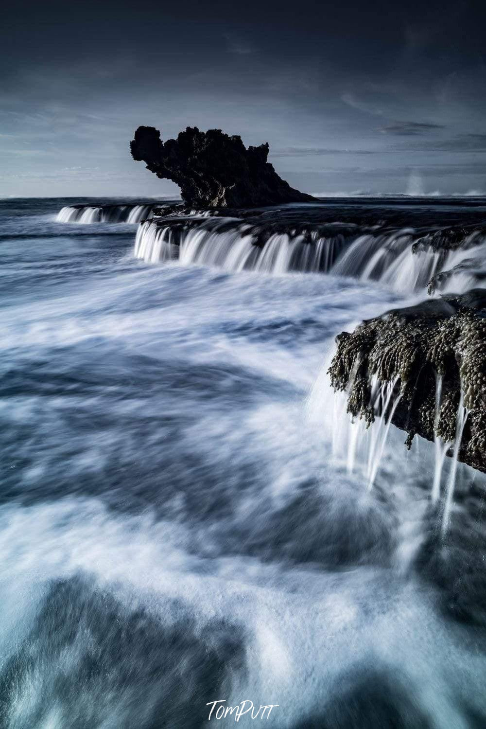 A breathtaking view of a long mountain wall with steady waterfalls passing over the wall, and a dragon's head like design is forming by the mountain in the background, Dragon's Blue, Rye - Mornington Peninsula VIC