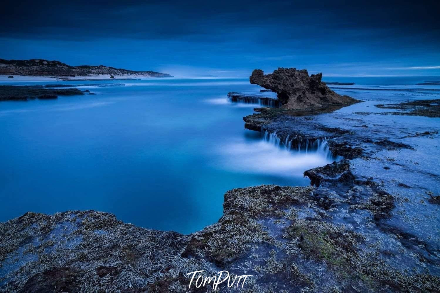 A low light view of rocky land with an ocean inside and a dragon's head like design is forming by the mountain in the background, Dragon's Dawn, Rye - Mornington Peninsula VIC