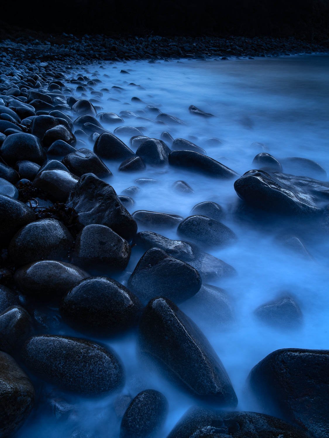 A series of countless number rounded stones placed on the edges of a huge watercourse, a low light effect with shiny moonlight hitting partially on the picture, Dreamy Shoreline, Bluestone Bay, Freycinet