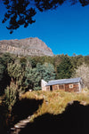 A green hill area with only house and a large mountain in the background, Cradle Mountain #35, Tasmania