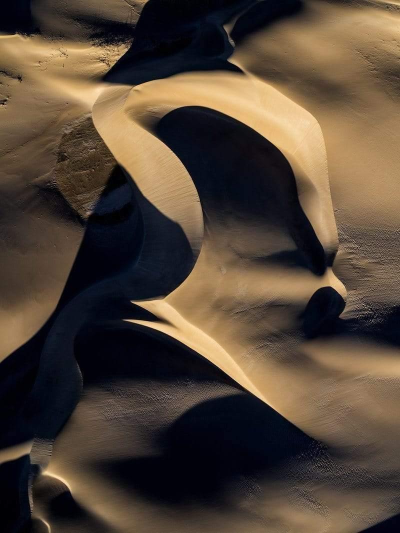 A giant python-shape forming by the sand of the desert, with some artificial light hitting partially on the picture, Dune Serpent
