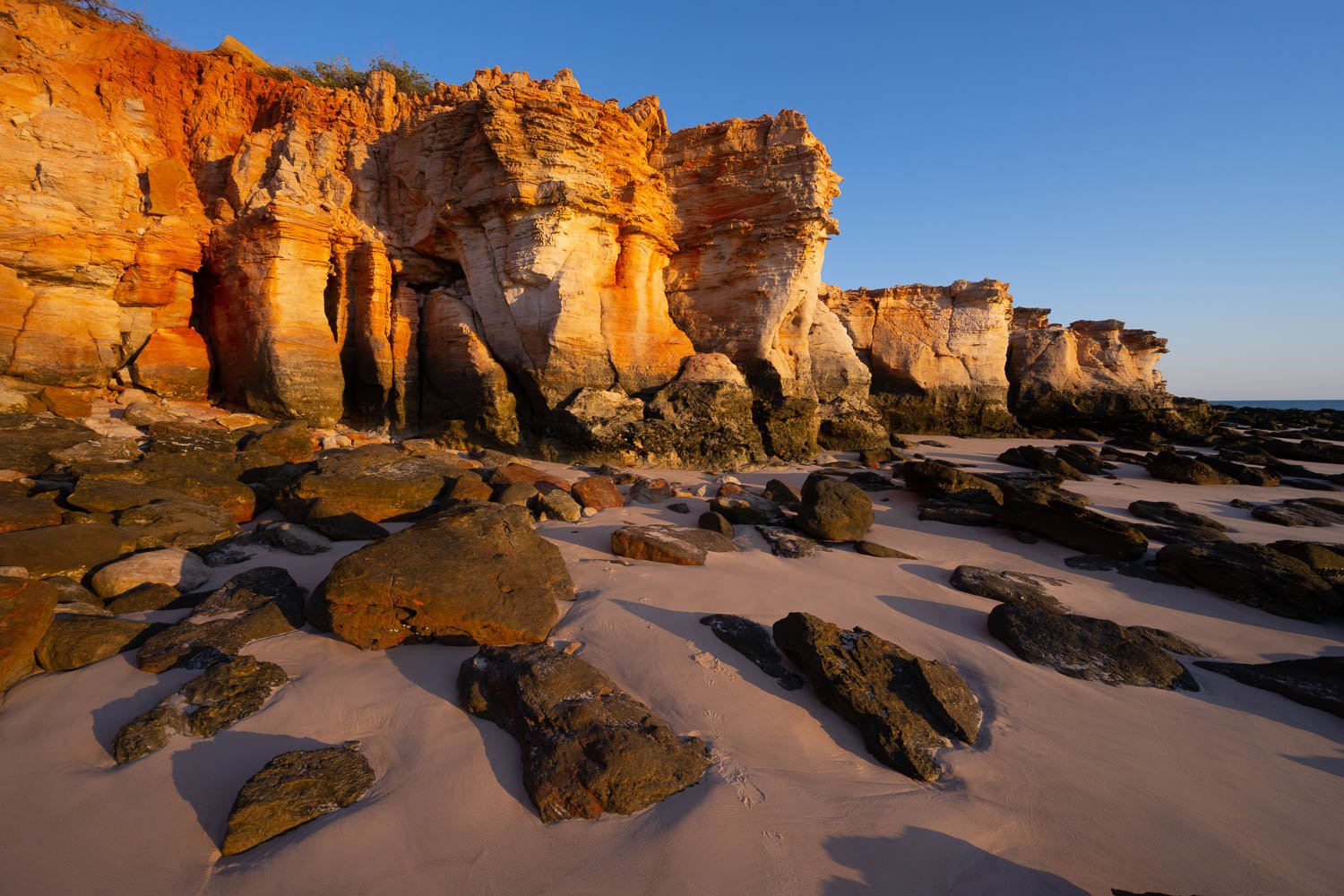 A long shiny mountain wall, a seashore land below the wall with a lots of small and large stones, Eastern Dawn, Cape Leveque, The Kimberley