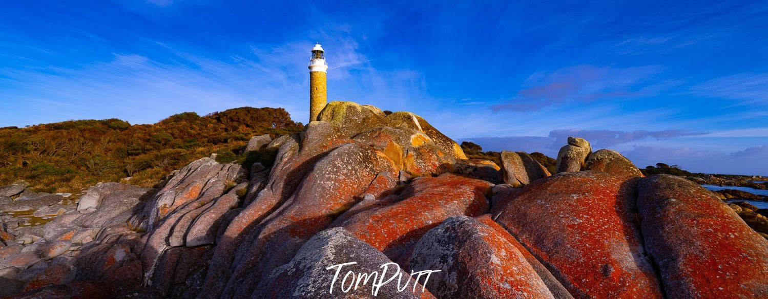 Lighthouse on the hill point of mountains, a lot of big red stones in the foreground, and a clear shiny weather, Eddystone Point Lighthouse, Bay of Fires