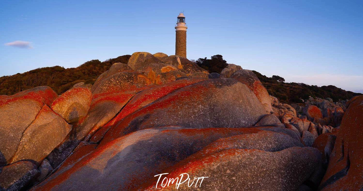 Lighthouse on the hill point of mountains, a lot of big red stones in the foreground, and a clear shiny weather, Eddystone Point Lighthouse, Bay of Fires