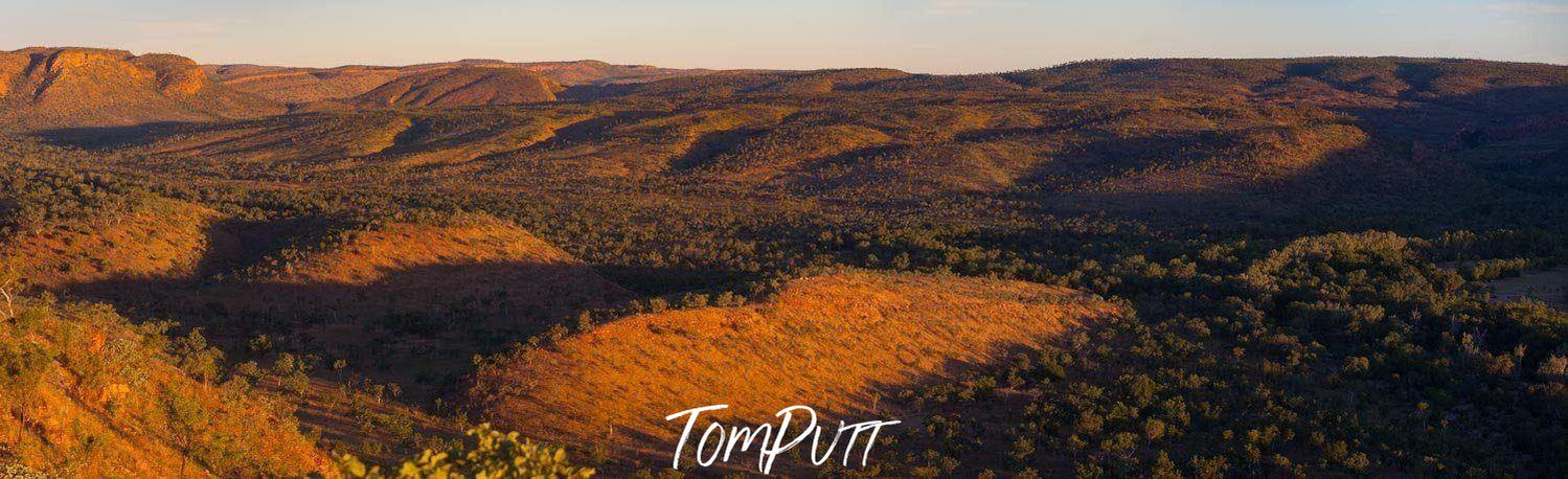 A landscape view of a desert-like land and a spreading grass on the far background, and some mounds of sand in with partially hitting sunlight, El Questro Station - The Kimberley WA