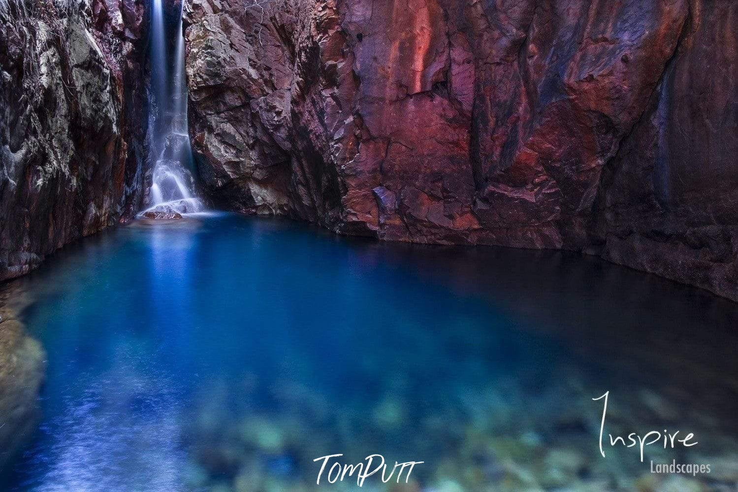 A crytsal blue water lake under the mountain walls, a little waterfall on the front corner, El Questro Waterfall - The Kimberley WA