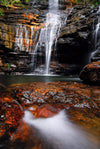 A beautiful waterfall from rock of orange and dark brown shade, some flat stones on the ground with the overflow of the water, Empress Falls #2 - Blue Mountains NSW
