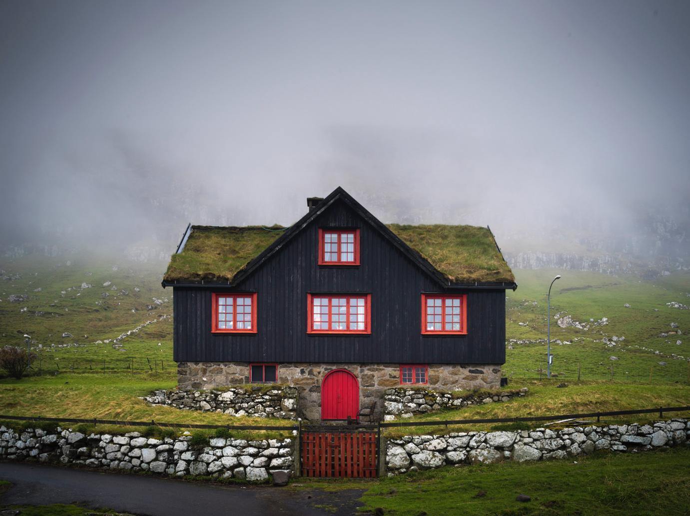 A beautiful house of black color with red outlines of windows, and a grassy roof, A greenfield area with nothing but a foggy effect in the background, Faroes Islands House 