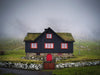 A beautiful house of black color with red outlines of windows, and a grassy roof, A greenfield area with nothing but a foggy effect in the background, Faroes Islands House 