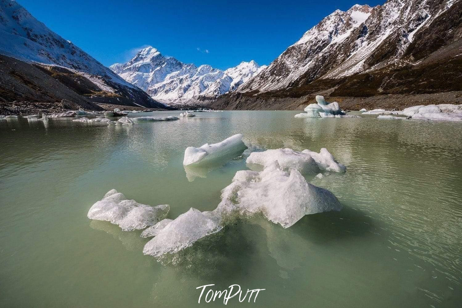 A cold lack between the snowy mountains, some small crystal ice floating on water, Floating Bergs New Zealand Art