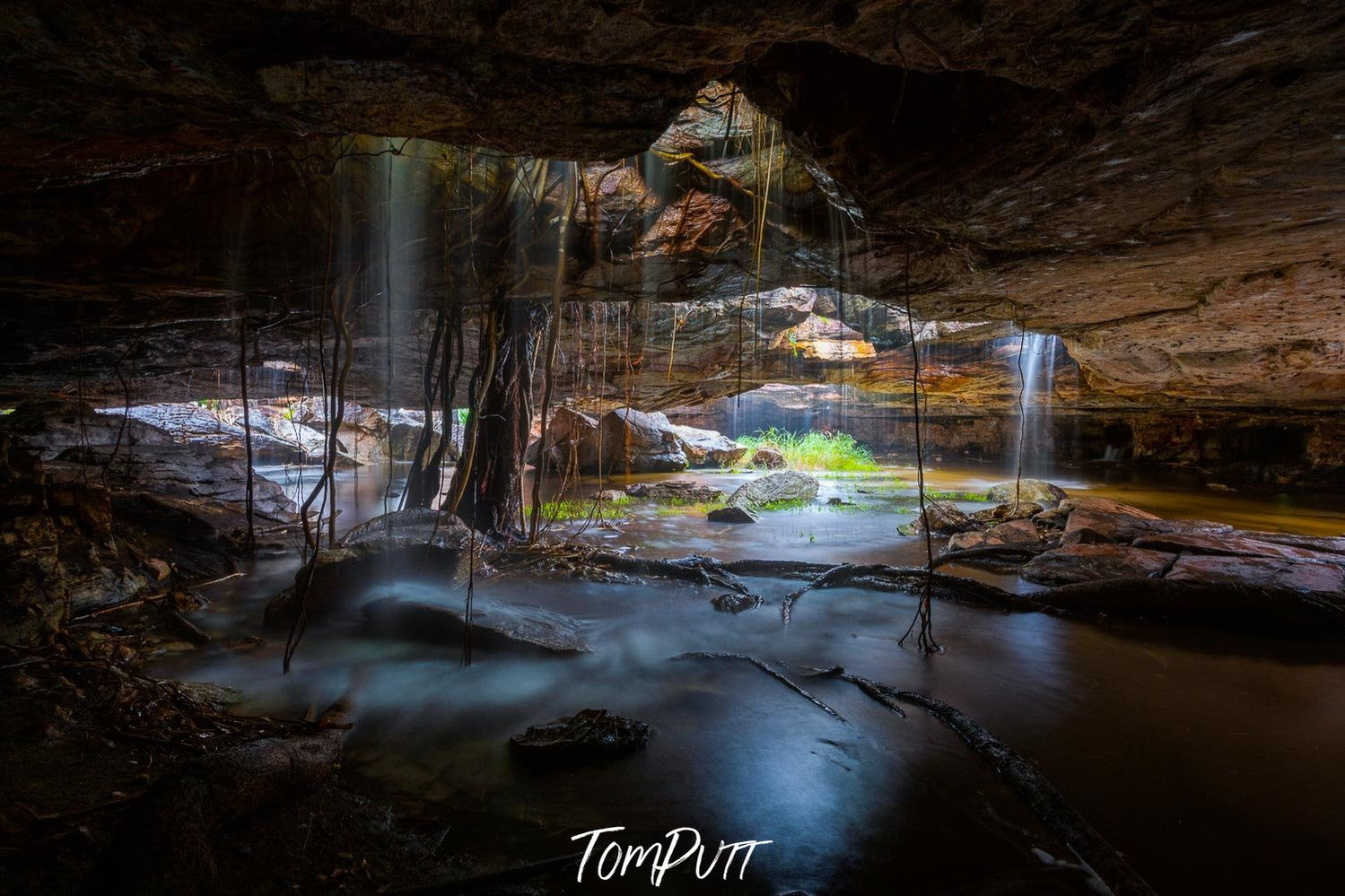 The area under a rocky mountain with some holes that are passing the water and the sunlight inside, Arnhem Land 6 - Northern Territory 