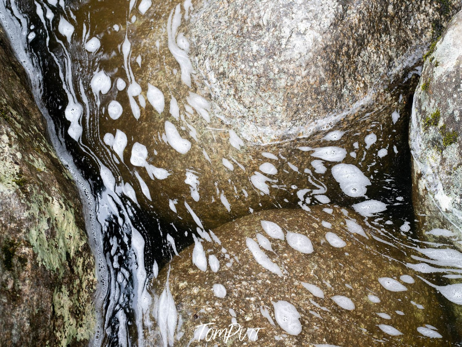 Clean water with small bubbles standing over some rounded rocks, Foam on water, Babinda Boulders, Far North Queensland