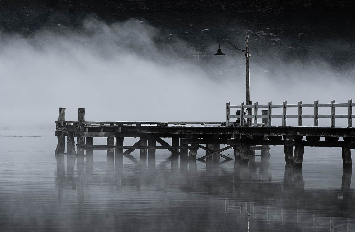 Dark view of a wooden bridge over a lake with clear reflection in the water, New Zealand #6