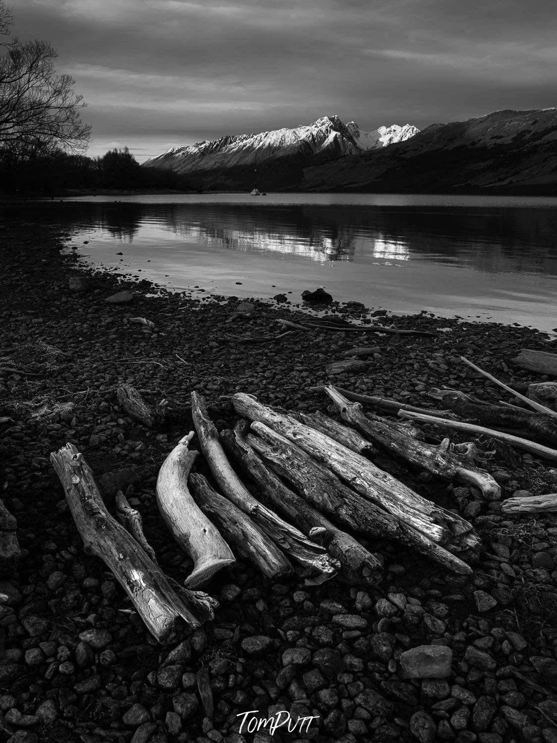 Dark view of a lake, some long wood pillar, and a mountain wall in the background, Glenorchy Shoreline - New Zealand