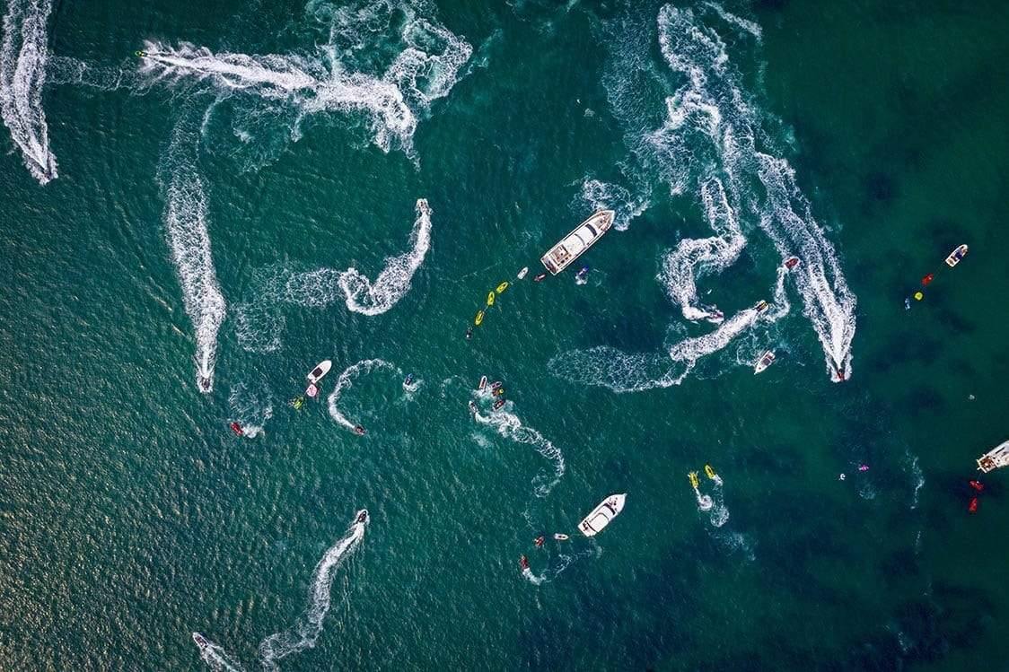 Aerial view of an ocean with many boats running in a rounded shape, Going Mad, The Pillars - Mornington Peninsula VIC