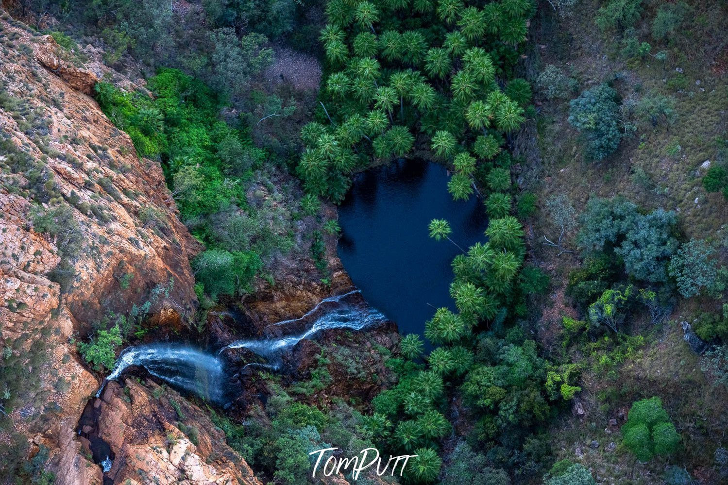 Aerial view of deep lake sorrounded with high mountain walls, and some patterns of wild plants 