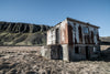 An old house on sand with long greeny mountains in the background, Iceland #13