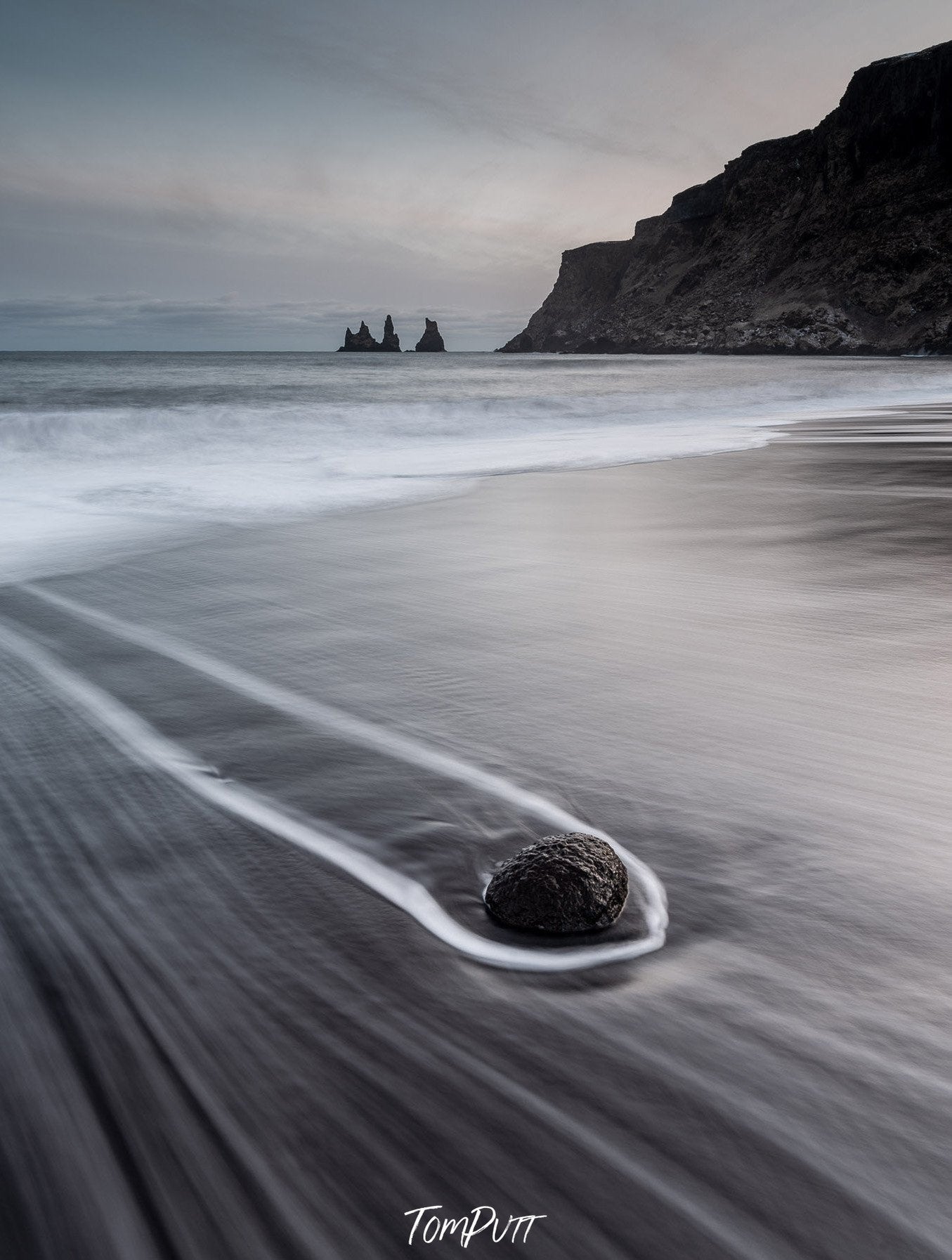 A dark view of a beach with a rounded stone dragging, and a giant mountain in the background, Iceland #22