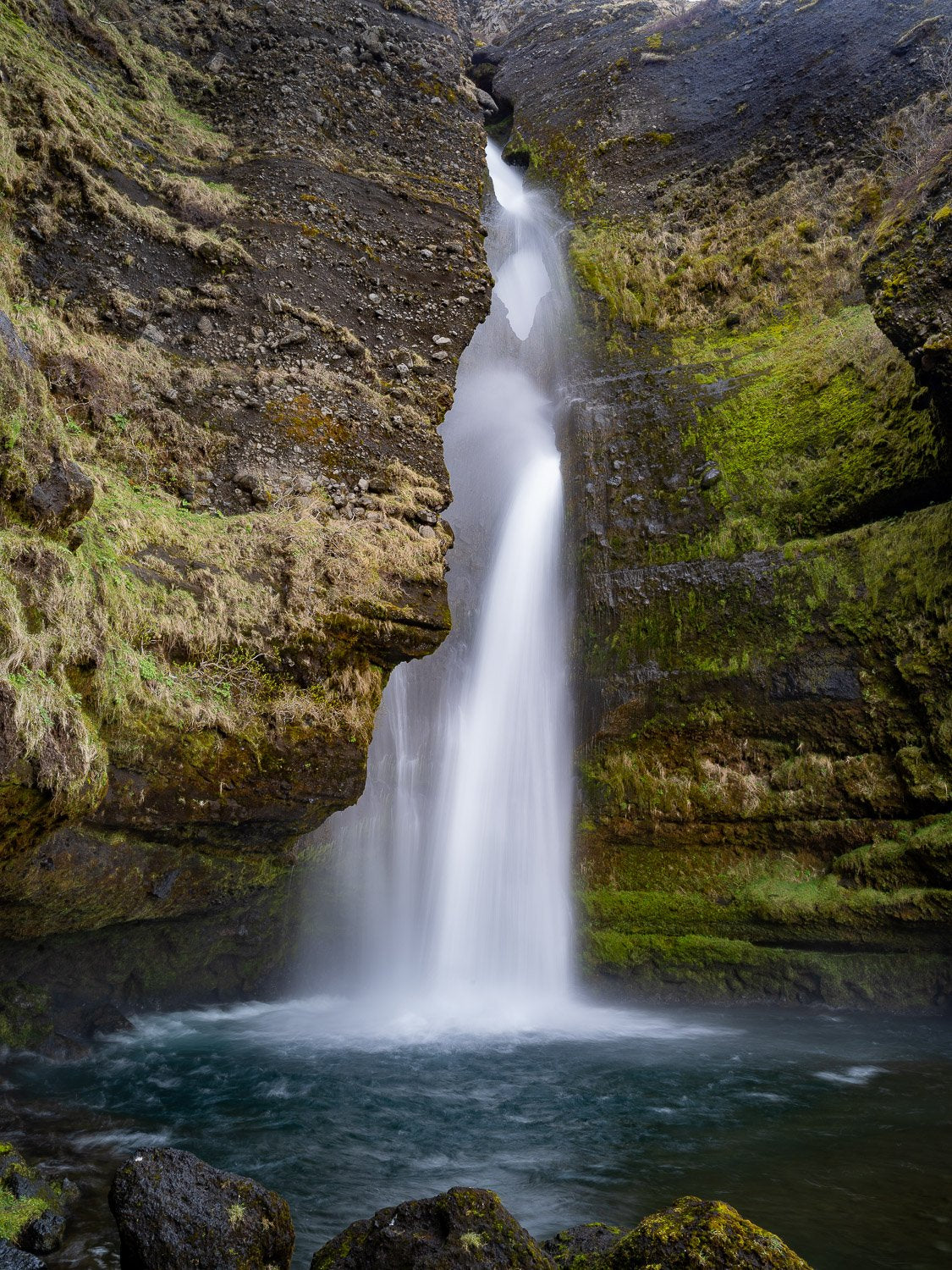 A beautiful waterfall coming from a hill area of a tall mountain wall, Iceland #32