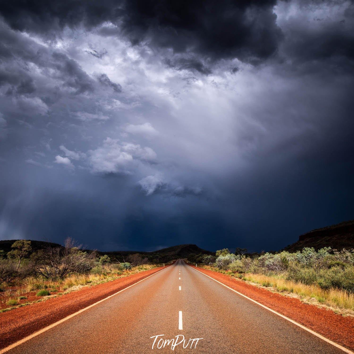 Empty road following a dark dense group of clouds, Karijini Road - Karijini, The Pilbara