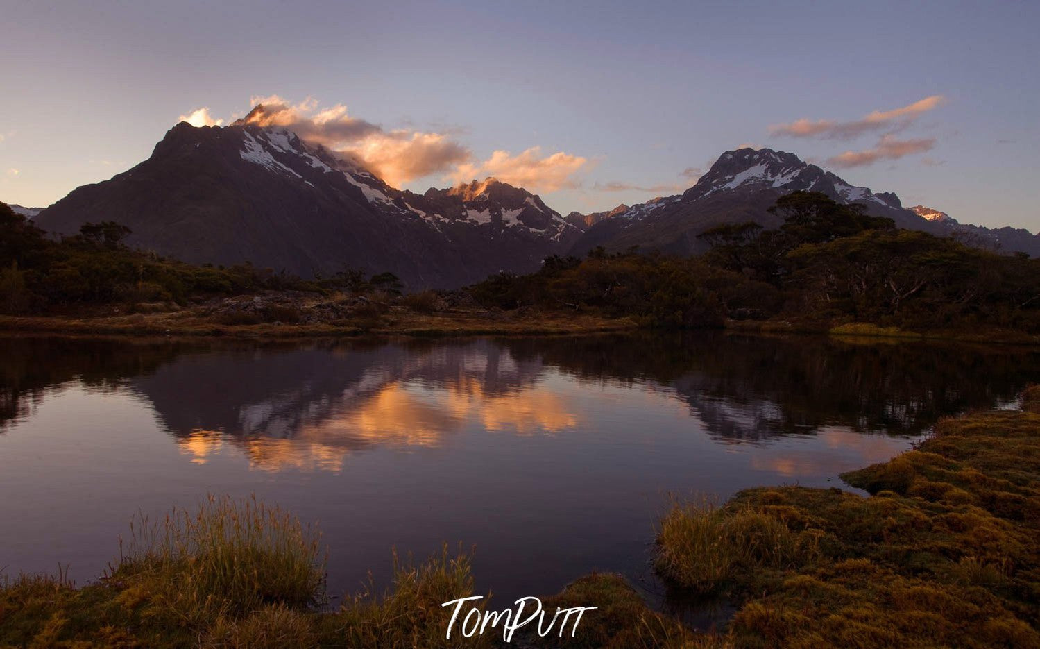 Beautiful series of mountains with a lake ahead them, a lot of greenery in the foreground, Key Summit reflection at sunset, Routeburn Track - New Zealand