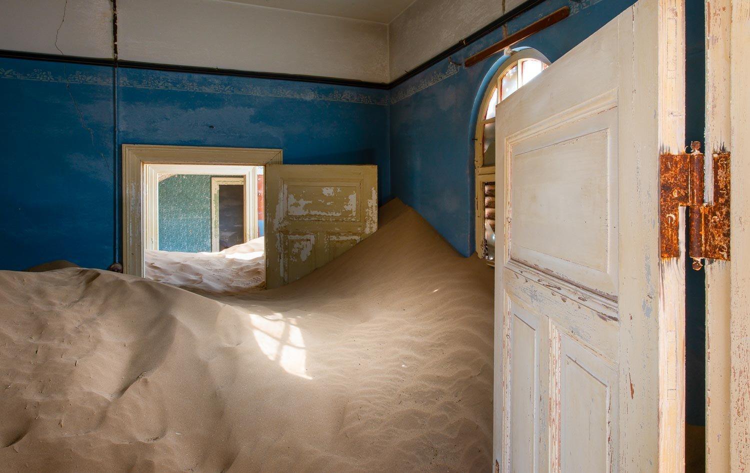 Making of a house room with open doors and a lot of construction sand inside, Kolmanskop #27