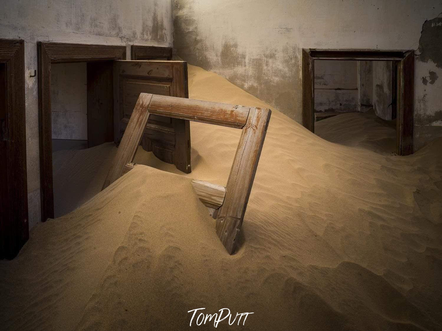 Making of a house with a lot of construction sand inside, and a broken door inside the sand, Kolmanskop #3 - Framed