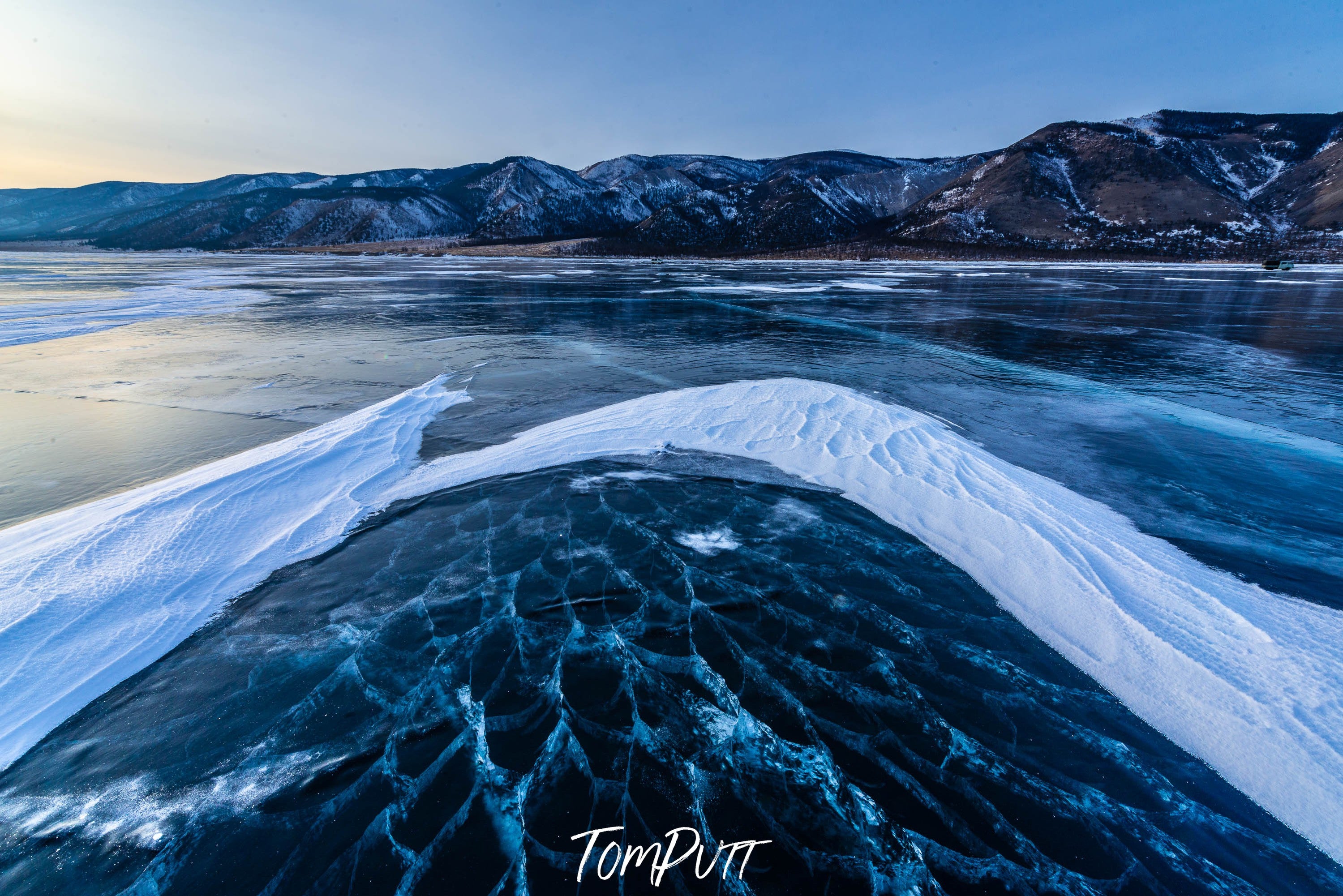 A frozen lake with some fresh snow, and a long mountain wall in the background, Lake Baikal #27, Siberia, Russia