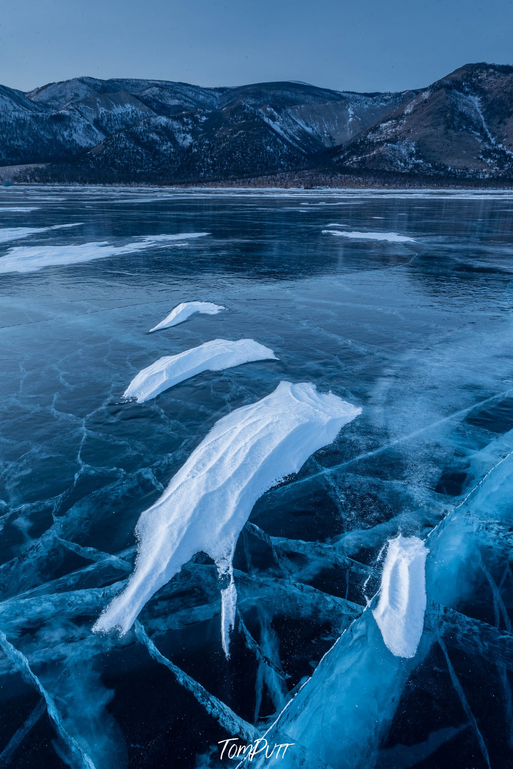 A frozen lake with some fresh snow, and a long mountain wall in the background, Lake Baikal #28, Siberia, Russia