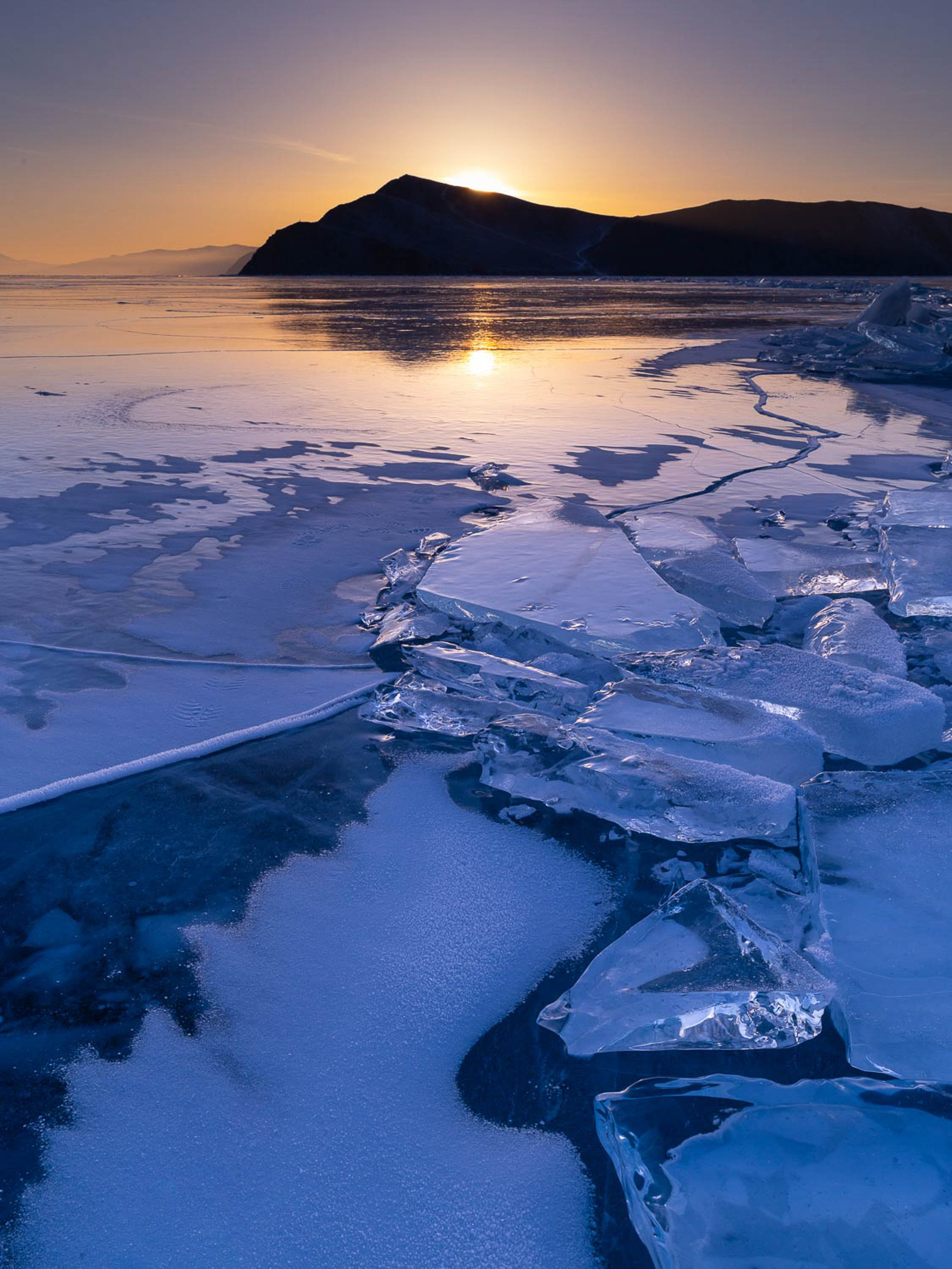 A cold lake with many crystalline ice pieces on it, and a long mountain wall with sunset besides, Lake Baikal #53, Siberia, Russia