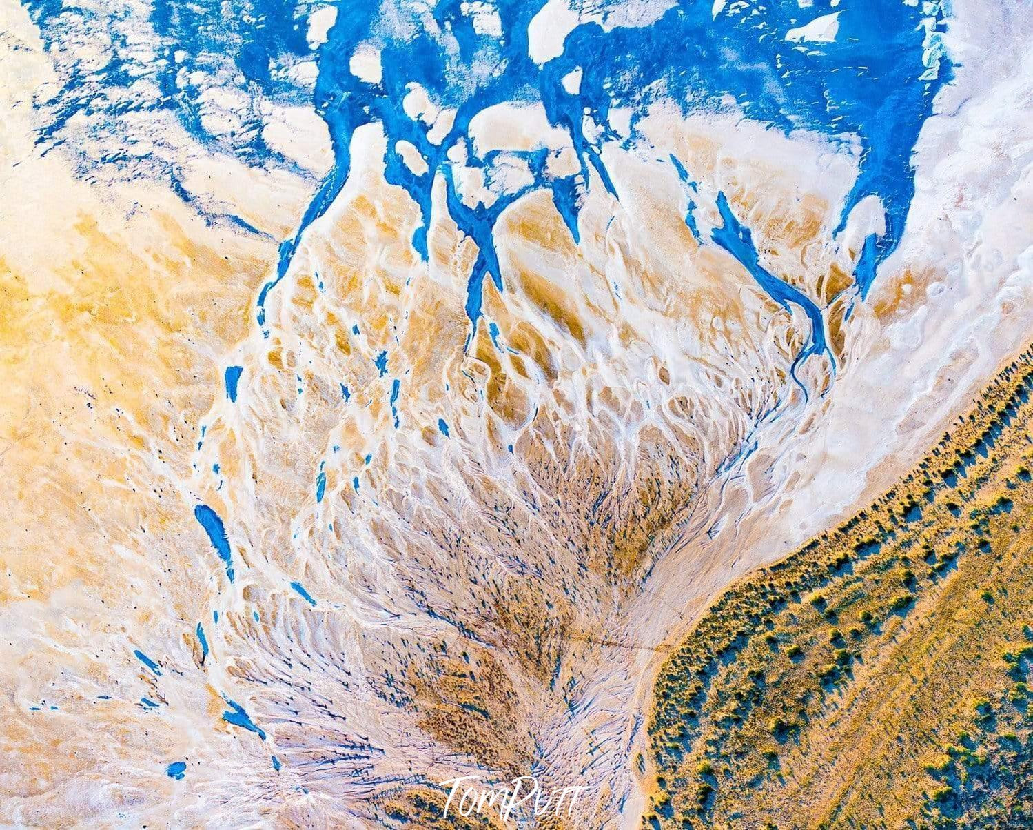 Aerial view of a lake covered with white surface, and a green area on the right side, Lake Eyre Delta