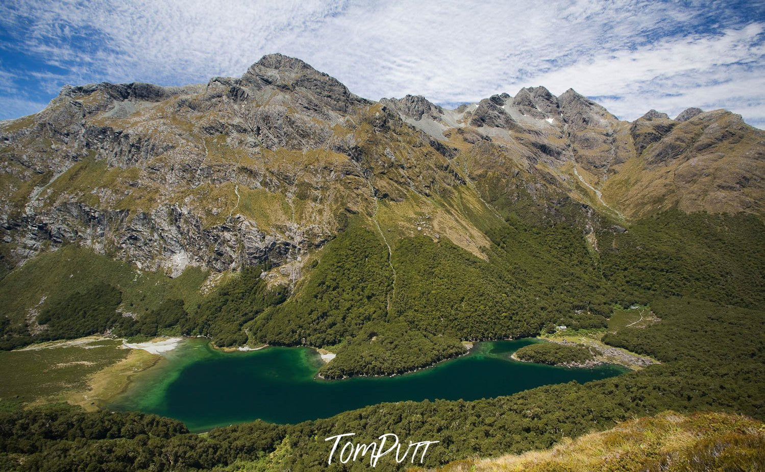 Giant green mountains with a small lake below, Lake MacKenzie from high above the Routeburn Track - New Zealand