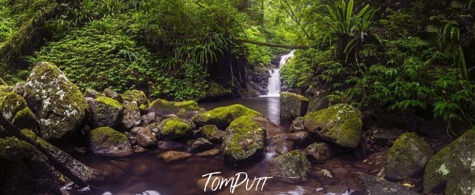 Long sequence of small greeny stones, and a small waterfall into a lake in the background, Lamington Waterfall Panoramic QLD