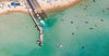 Aerial view of a sea-green beach with many people and boats, Launching Place, Safety Beach - Mornington Peninsula VIC