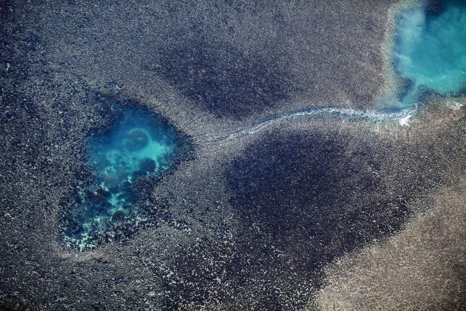Aerial view of a rocky land with two unique small natural pools full of ice-blue water, Linked Pools