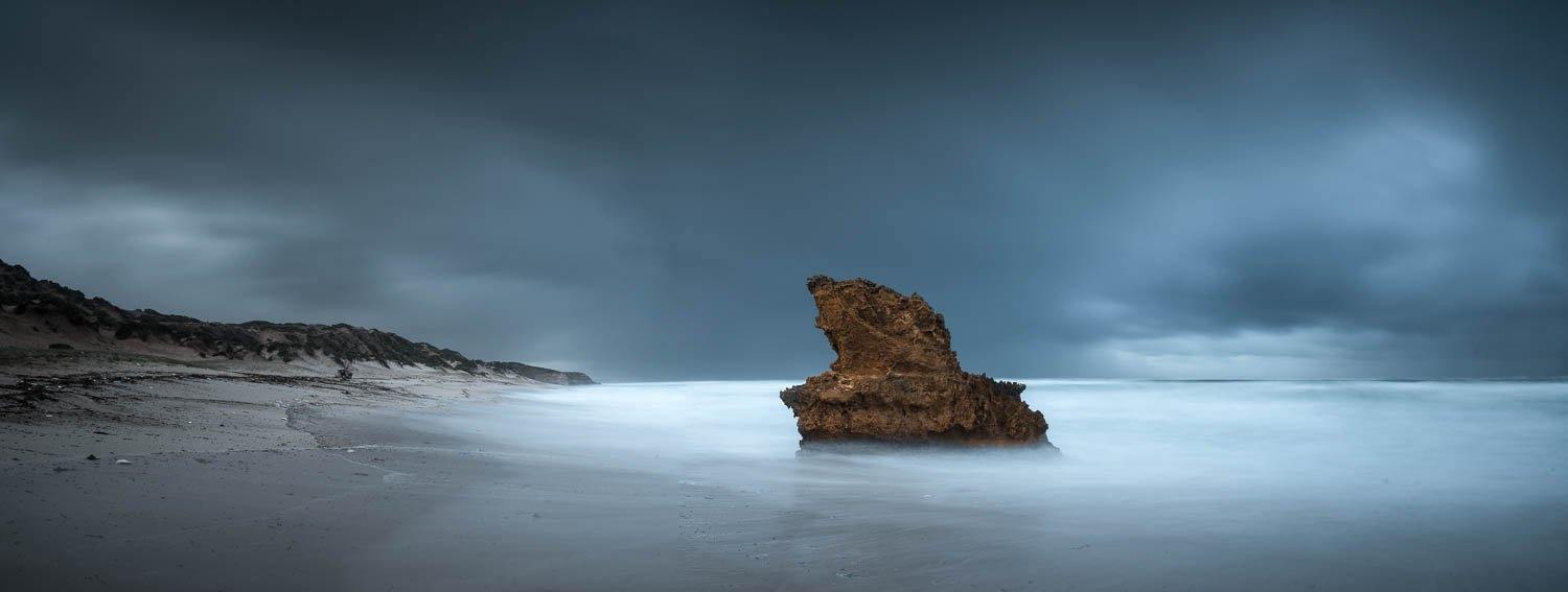 Large mountain standing in the middle of a sea with thick black clouds over, Lizard Rock Storm - Mornington Peninsula VIC