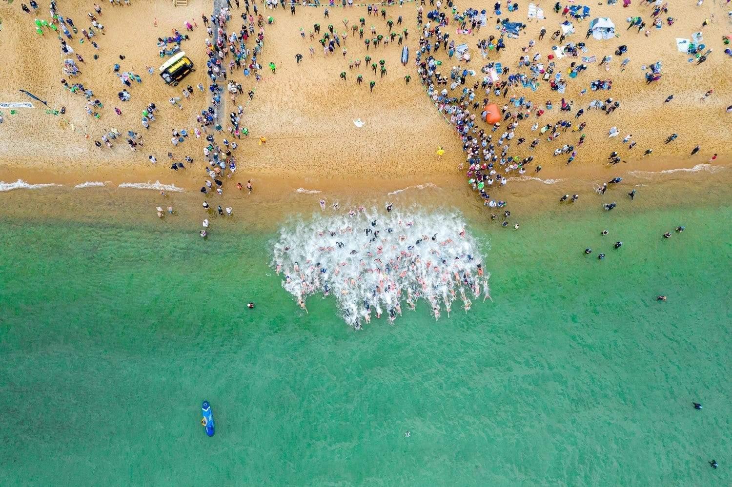 Aerial view of a green water beach with a lot of people, MMAD Swim Start from above - Mornington Peninsula VIC