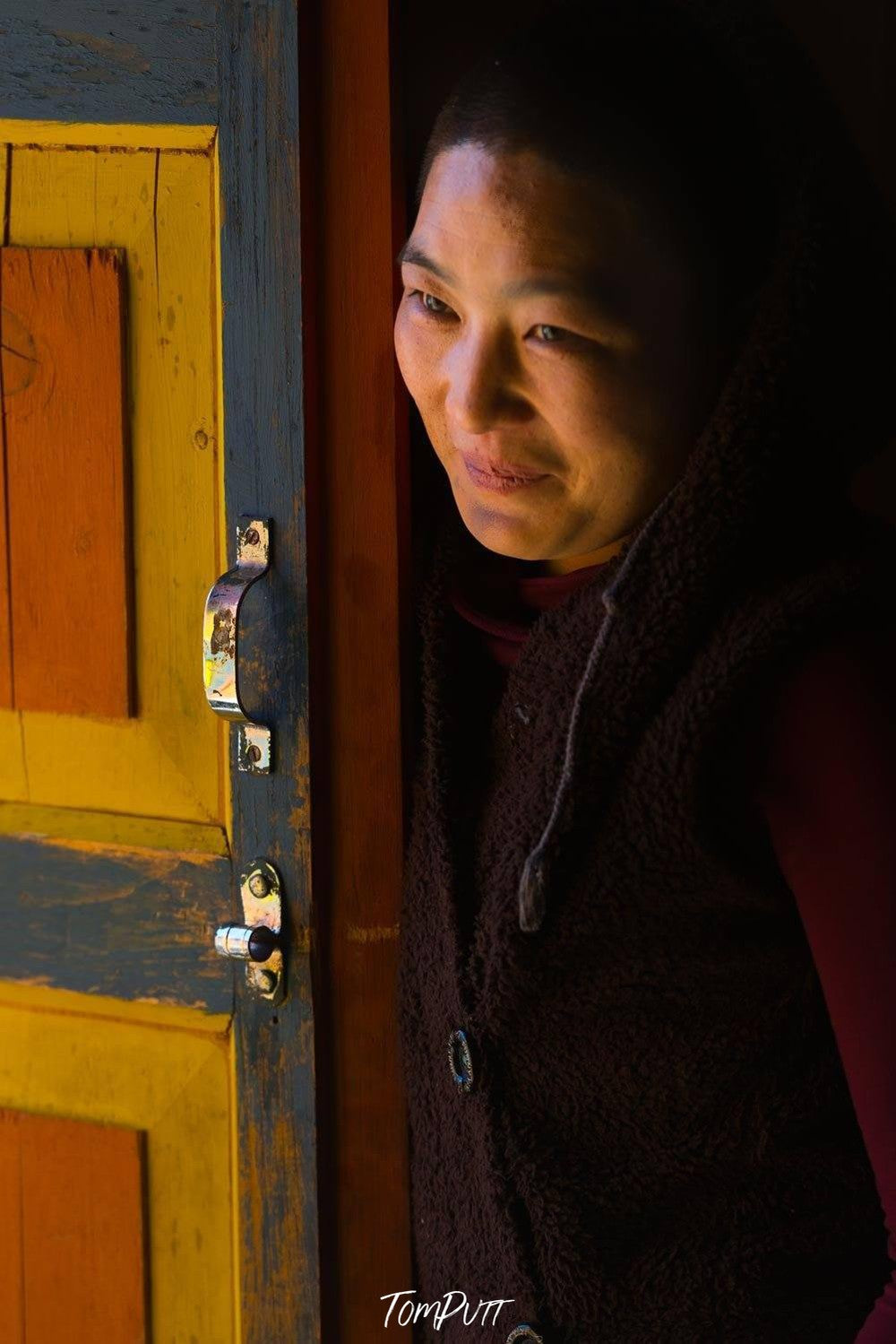 Smiling lady beside an opened door, Monk in Light, Bhutan