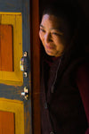 Smiling lady beside an opened door, Monk in Light, Bhutan