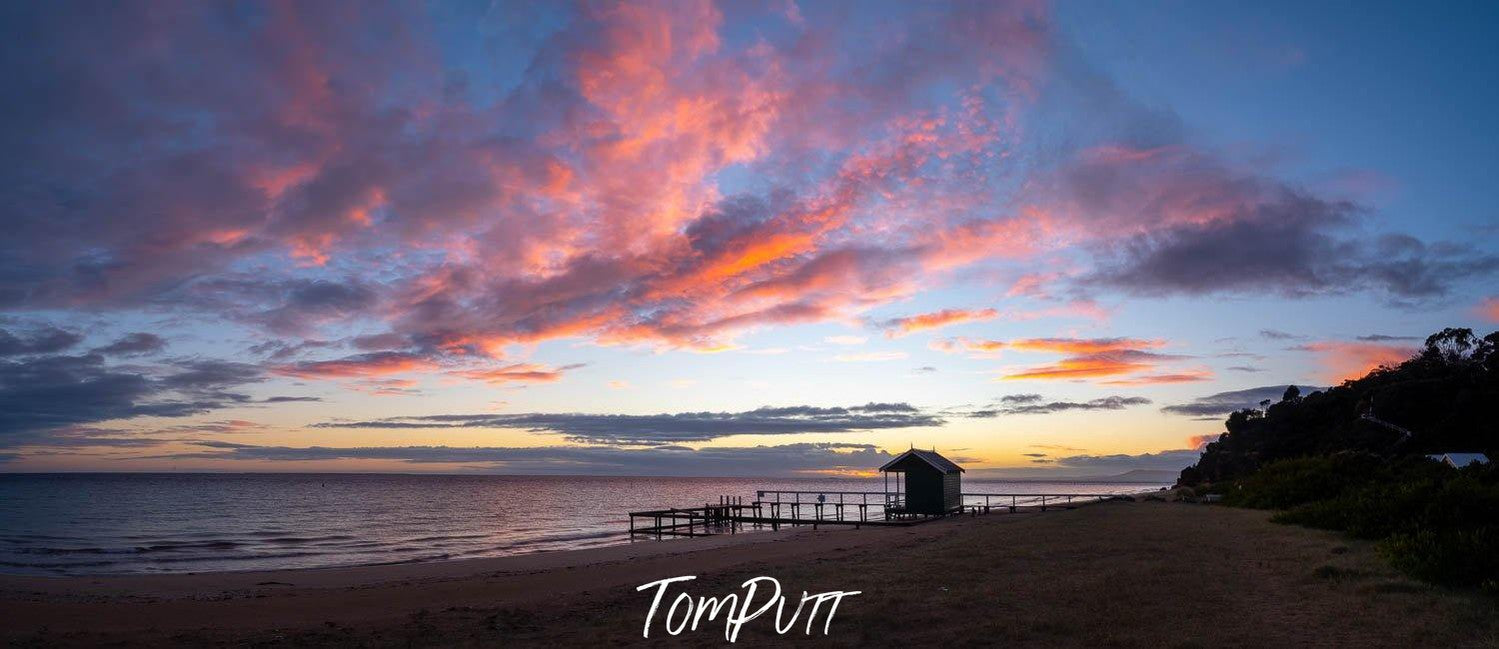 Long shot of a sea with a hut at the shore, and a purplish shade in the sky, Morning Glow at Point King, Portsea - Mornington Peninsula VIC 