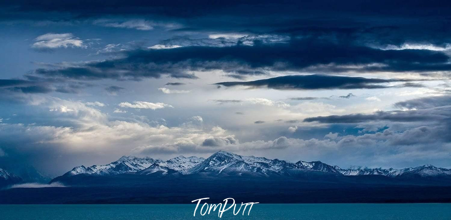 A long shot of solid blue mountain walls with heavy dense clouds over, Mount Cook Clouds - New Zealand