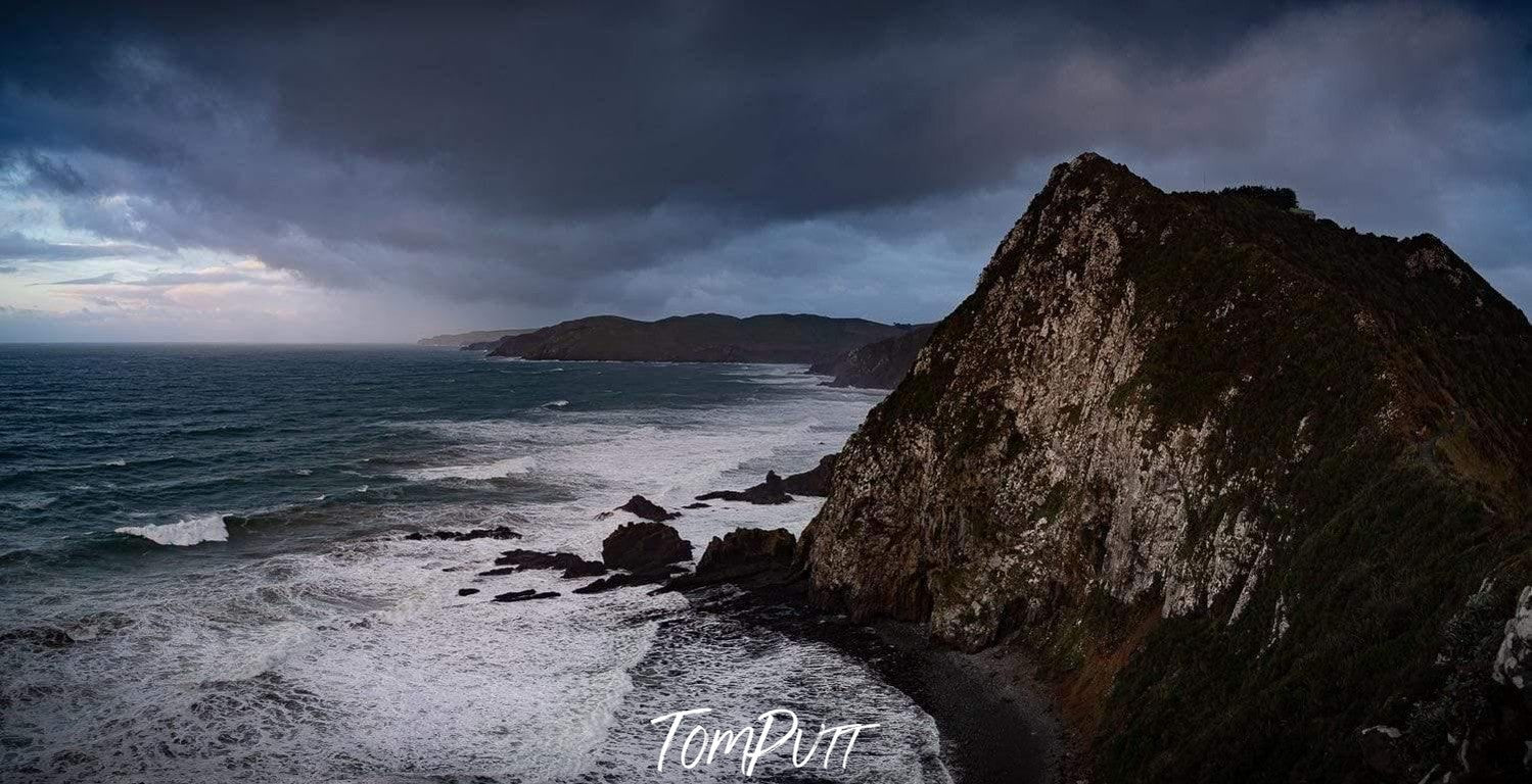 A dark mountain rock in a lake with dense thick clouds, Nugget Point New Zealand Art