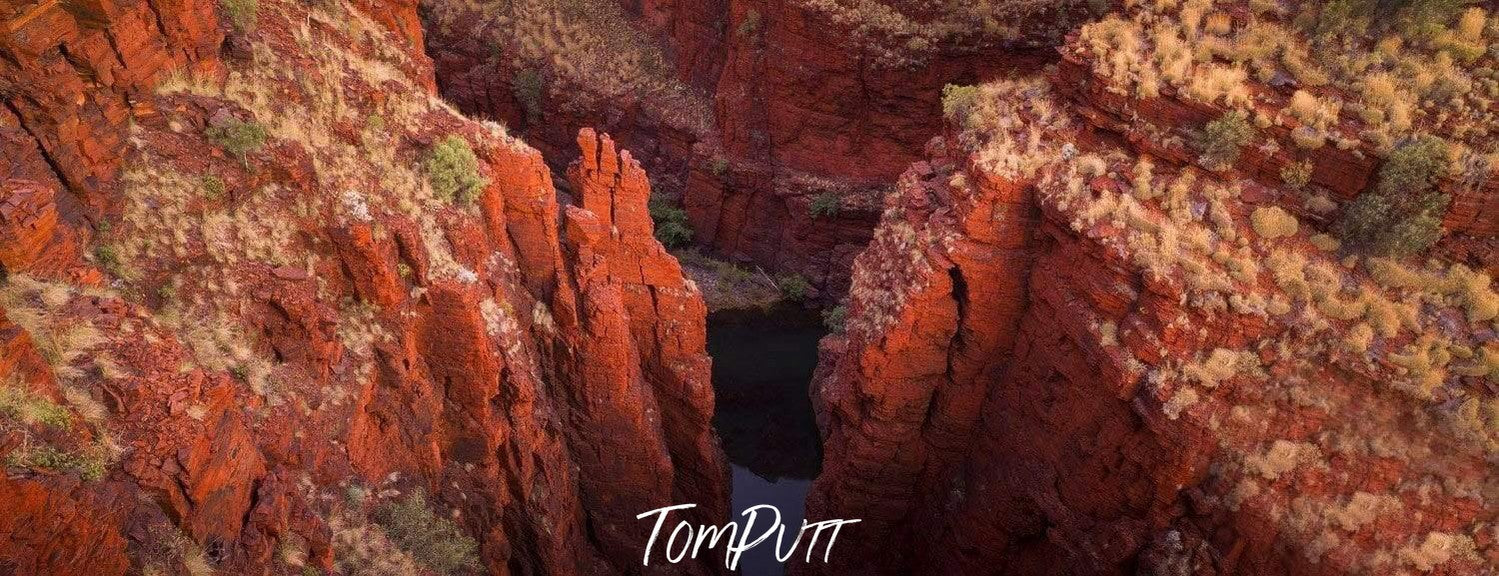 Aerial view of the peaks of giant mountain walls with a small water standing in a deep below, Oxer Lookout - Karijini, The Pilbara