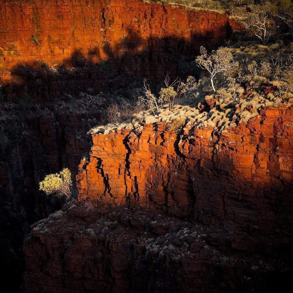 A drone view of an orangish-bricked mountain having some greenery over, with partially hitting sunlight, Oxers Sunset - Karijini, The Pilbara