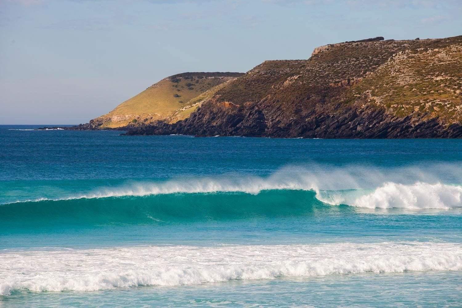 Beautiful bubbling waves in a sea with a huge mountain wall behind, Pennington Bay Surf - Kangaroo Island SA