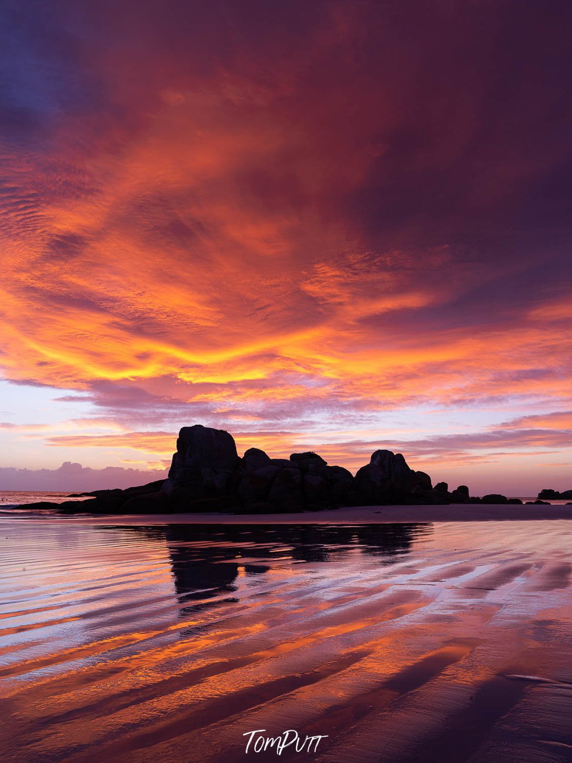 Dark mountains with a dense orangish and reddish effect of clouds over, Picnic Rocks sunrise, Bay of Fires