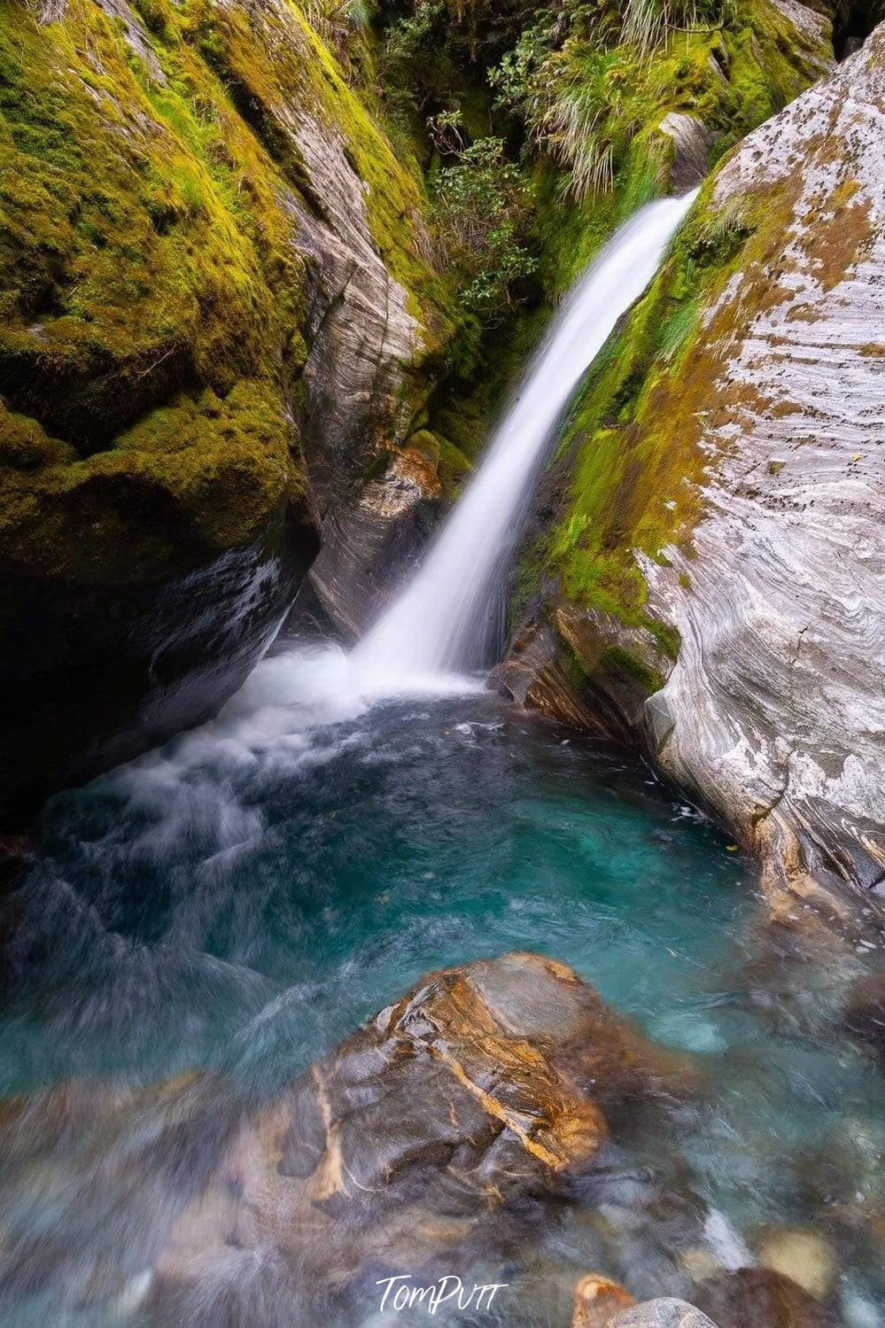 Waterfall from a high green mountain wall in a crystal clear lake, Plunge Pool, Milford Track - New Zealand